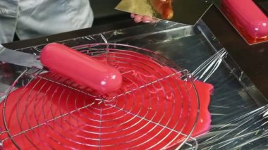 Şekerci elleriyle küçük oval pastayı altın tezgahın üzerine pembe ayna jöleli koyar.