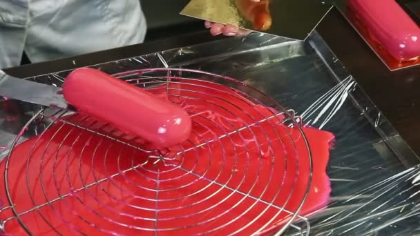 Confitero a mano pone pequeño pastel ovalado con esmalte espejo rosa en soporte de oro — Vídeo de stock