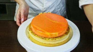 Şekerci, turuncu kaplı yuvarlak peynirli keki küçük sarı badem kurabiyeleriyle süslüyor.