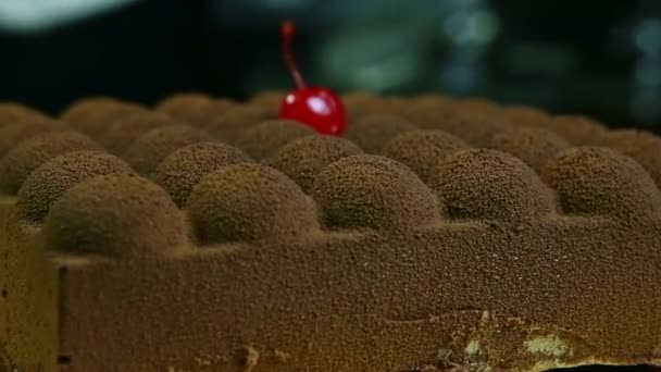 Close-up originele vierkante chocolade taart met enkele rode kers decoratie — Stockvideo