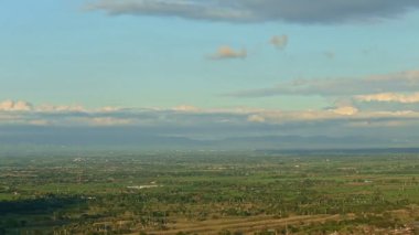 Rüzgarda yavaş yavaş panorama, dağların tepesindeki yumuşak bulutlara karşı palmiye yapraklarını sallar.