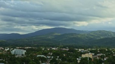 Dağlar ve kabarık bulutlar arasında yeşillik olan küçük bir kasabada yavaş yavaş panorama
