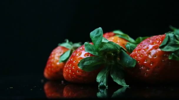 Close-up panorama op groep van hele rijpe rode aardbeien op zwarte achtergrond — Stockvideo