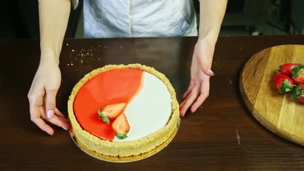 Confeiteiro por mãos mostra todo o cheesecake redondo de vidro vermelho e branco — Vídeo de Stock