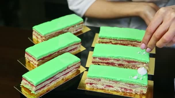 Process of decorating green glazed cake portions by white crashed bizet — Stock video