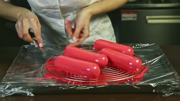 Confitero toma uno de cuatro rosado esmaltado pastel oval servido en soporte de metal — Vídeo de stock