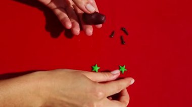 Kadın ellerine tepeden bakıldığında renkli badem ezmesinden patlıcan şekilli şeker yapılır