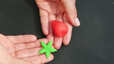 Üst kattaki yakın plan kadın elleri kırmızı çilek şekilli badem ezmesi şekeri yapıyor.