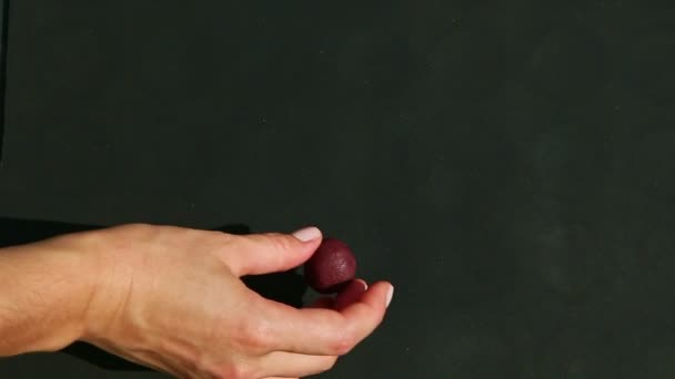 Vista dall'alto sulla mano della donna mette uno per uno piccolo pezzo di marzapane viola — Video Stock