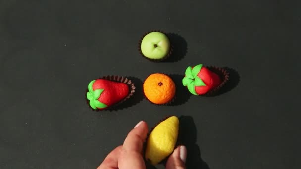 Eldeki üst görünüm meyve şekilli badem ezmesi şekerlerini çeşitlilikten ayırıyor — Stok video