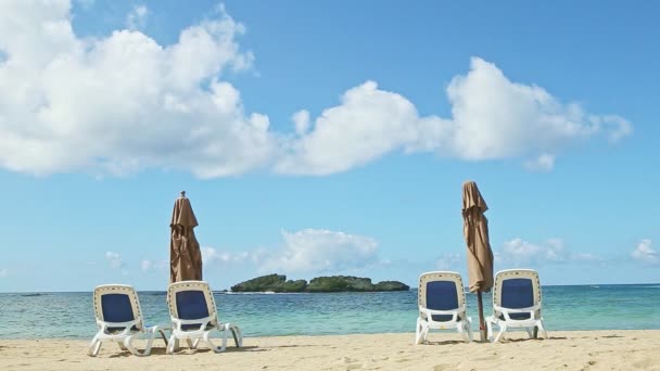 Grandi nuvole soffici volano sopra l'oceano e sabbia con sedie a sdraio e ombrelloni chiusi — Video Stock