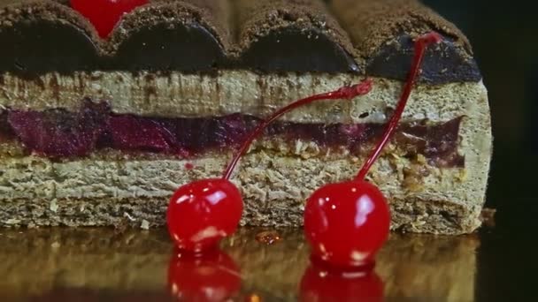 Macro view focus in at red double cherry against half of modern chocolate cake — Stock Video