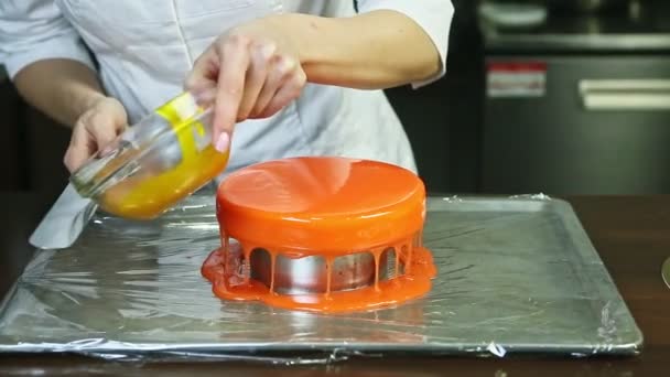 Confitero decora pastel de queso redondo esmaltado naranja por glaseado dorado líquido — Vídeo de stock