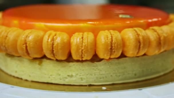 Closeup egész kerek narancs mázas torta mini macaroons forog körül — Stock videók