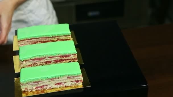 Confiseur par les mains met des portions de gâteau crémeux aux fruits verts glacés — Video