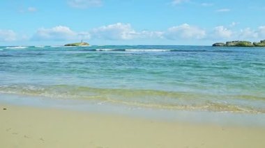 white fluffy clouds above blue ocean with waves and golden sand beach