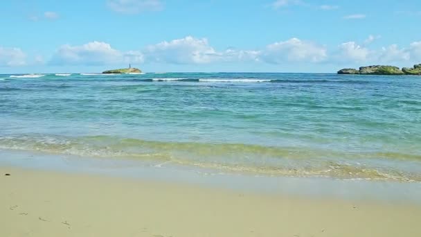 Nubes esponjosas blancas sobre el océano azul con olas y playa de arena dorada — Vídeo de stock