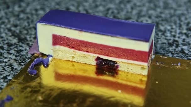 Pedazo de pastel de postre esponja con mousse blanco y baya rematado con gelatina violeta — Vídeos de Stock