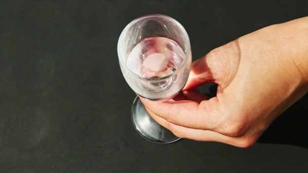 Верхний вид женщина рука кладет один высокий хрустальный бокал вина с водой и забирает его — стоковое видео