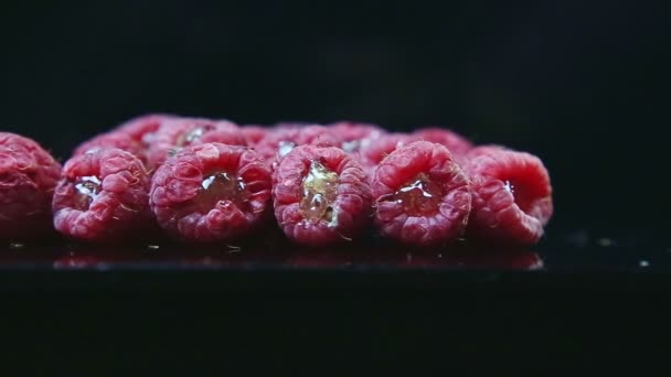 Nahaufnahme-Panorama bei einer Gruppe frischer Himbeeren, die mit Gelee auf schwarz serviert werden — Stockvideo