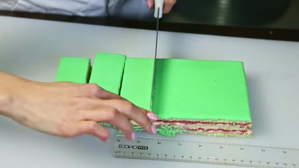 Confiseur découpé en portions par couteau gâteau glacé vert avec garniture fruitée crème — Video