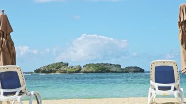 Yakın çekim kabarık bulutlar okyanusun üzerinde uçar kumsalda sandalyeler ve kapalı şemsiyelerle