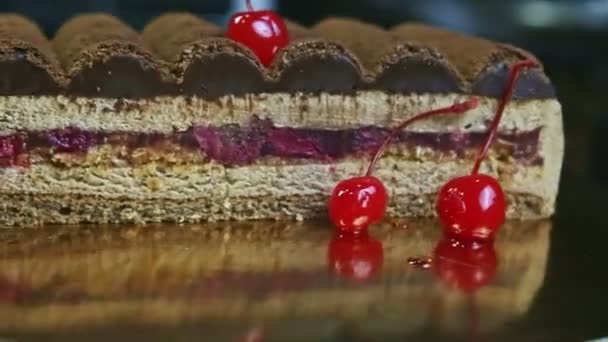 Närbild hälften av chokladkakan med dubbla körsbär roterar runt på gyllene stativ — Stockvideo