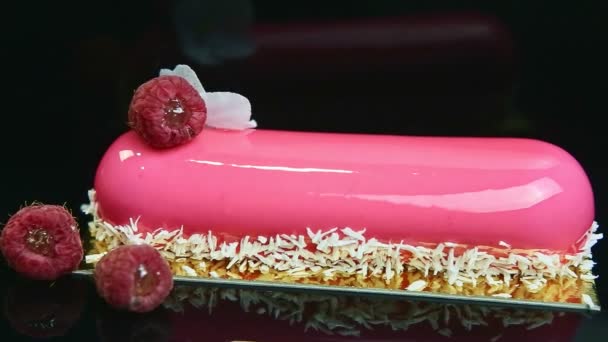 Close-up panorama bij roze geglazuurd dessert met kokosschaafsel en frambozen — Stockvideo