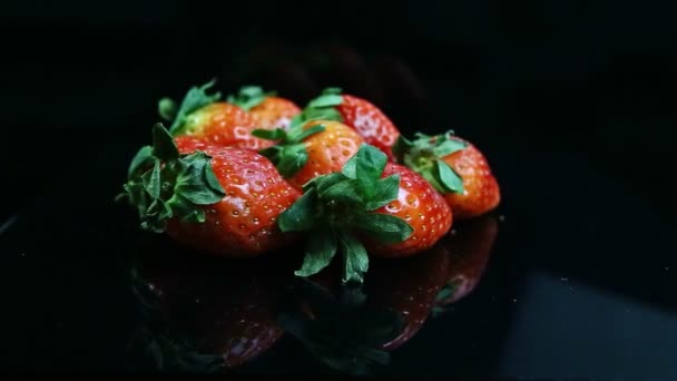 신선하고 딸기의 더미에서 반사광을 표면에 초록색 나뭇잎을 모습으로 모은다 — 비디오