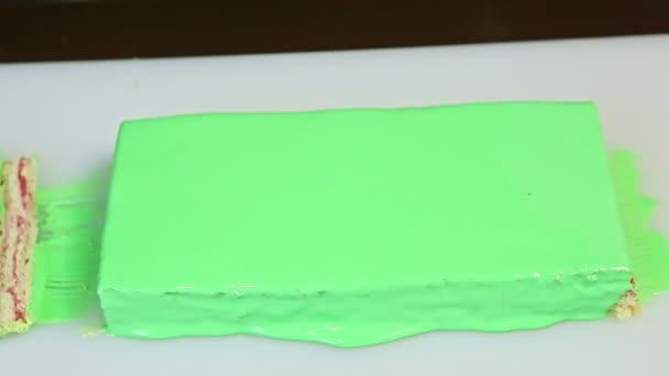 Top view closeup confectioner turns over white tray with green glazed layered cake — Stock Video