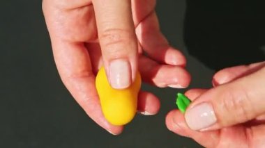 İnsan elinin üst görüntüsü armut şeklindeki ev yapımı badem ezmesi şekerini siyah masa yüzeyine karşı küçük yeşil bir yaprak yerleştirdi.