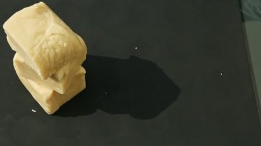 Kadın elinin üst görüntüsü siyah masaya altı küp beyaz badem ezmesi koyuyor.