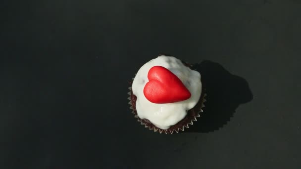 Top view on white glazed chocolate cupcake decorated with heart shaped candy — Stock Video