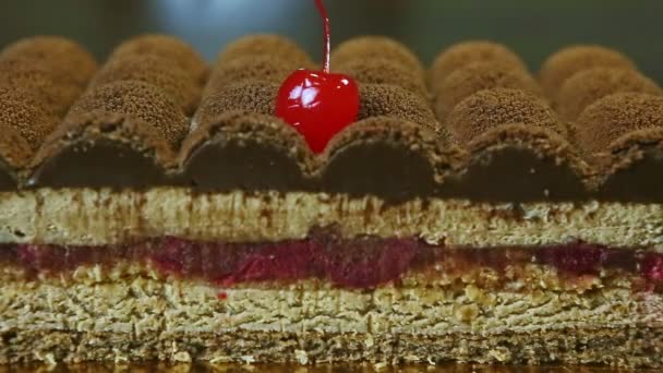 特写镜头集中在一半的现代形状的奶油慕斯蛋糕与水果樱桃果冻夹层装饰巧克力顶部和成熟的红樱桃 — 图库视频影像