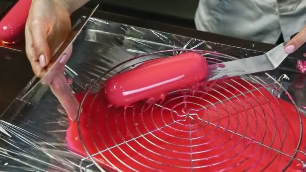 身穿白色制服的糖果工的顶视图是粉红釉面椭圆形釉料 放在现代厨房桌上的金属台面上 — 图库视频影像