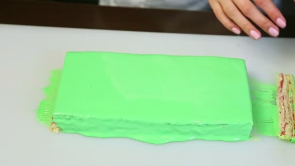 Banketbakker zet kleine plakjes gelaagde taart naast grote groene geglazuurde rechthoek — Stockvideo
