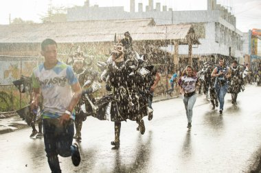 Concepcion De La Vega, DOMINICAN REPUBLIC - FEBRUARY 11, 2019: Çeşitli siyah kostümlü bir grup insan 11 Şubat 'ta Concepcion De La Vega' da Dominik Karnavalı 'nda şiddetli yağmur altında koştu