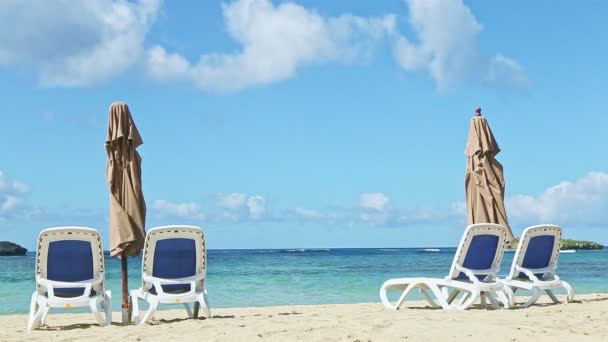 Pusty złoty piasek brzeg morza z długimi krzesłami plażowymi i zamkniętymi parasolami — Wideo stockowe