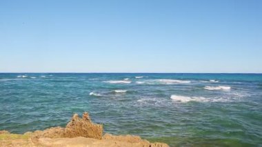 Sonsuz okyanustaki beyaz dalgalarda yavaş yavaş panorama kayalık sahillerinde parçalanır.