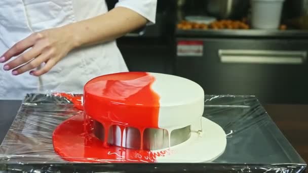 Confiseur en uniforme chef niveau sur glaçure miroir rouge et blanc sur gâteau au fromage rond — Video