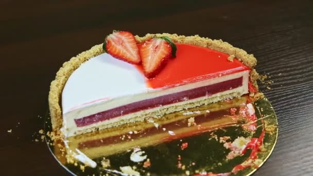 Lentamente panorama en la mitad de pastel de queso con capa intermedia de gelatina roja y glaseado colorido — Vídeo de stock