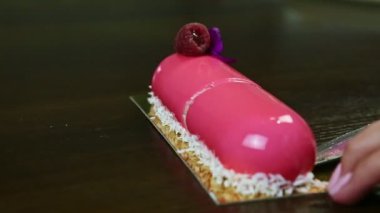 Şekerci bıçakla alıyor pembe camlı oval pastanın yarısını ahududulu