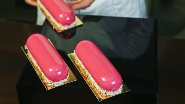 Confectioner serves three portions of pink glazed desserts with coconut shavings — Stock Video