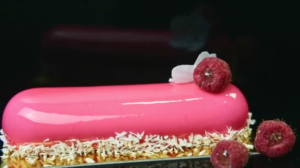 Primer plano panorama abajo en eclair acristalada rosa con virutas de coco y frambuesas — Vídeos de Stock