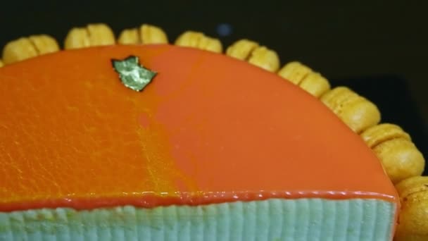 Closeup panorama down on half of orange glazed cheesecake on almond interlayer — Stock Video