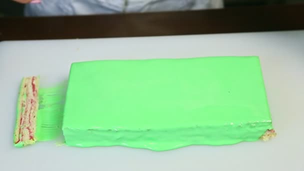 Κοντά τα χέρια κόβοντας με μαχαίρι μία άκρη του πράσινου γλασαρισμένου κρεμώδους κέικ — Αρχείο Βίντεο