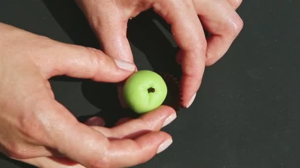 Vue supérieure sur les mains de la femme mettre des bonbons en forme de pomme massepain dans un support en papier brun — Video