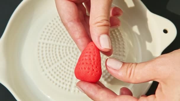 Top view closeup hands show and take away red strawberry shaped marzipan candy — Stock Video