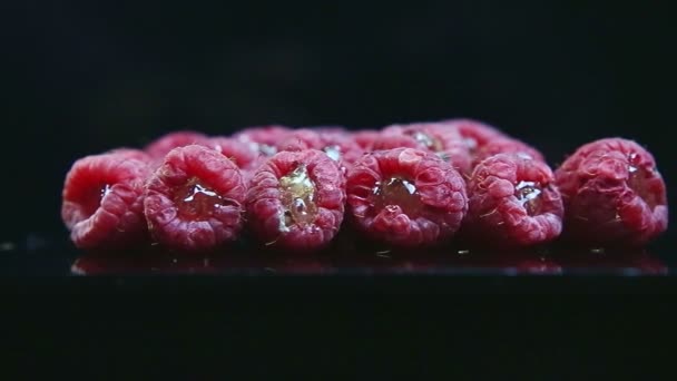 Panorama de primer plano en la pila de frambuesas frescas dotadas de gelatina servida sobre negro — Vídeo de stock