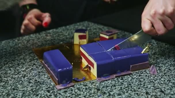 Vrouw handen door mes snijd op stukken violette geglazuurde mousse cake met gelei tussenlaag — Stockvideo